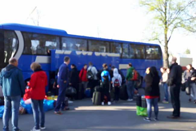 Blauer Turnierbus mit Jugendlichen, die ihre Tasche einräumen